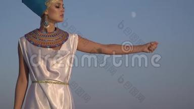埃及伟大的纹身女王站在天空的背景下释<strong>放出</strong>一把沙子。慢动作